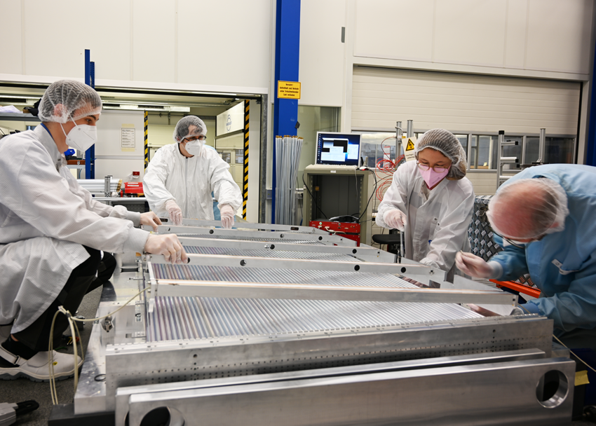 Team work in the clean room: MPP employees are mounting an optical measuring system onto the drift tube layers. It monitors potential deformations due to the self-weight of the muon chamber. The signal wires in the drift tubes are positioned with an accuracy of 1 hundreth of a millimeter. (Photo B. Wankerl/MPP)